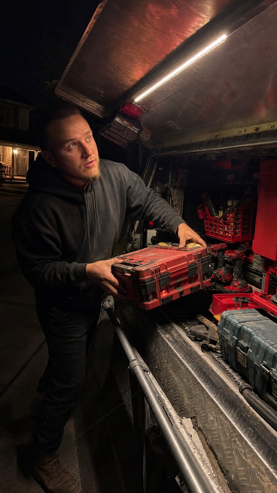 Tradesperson grabbing a tool case from a canopy lit by a LockLite at night